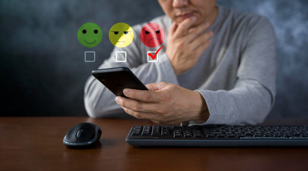 Insatisfaction client suite à des pain points Homme utilisant son smartphone pour donner une note inférieure suite à un pain point.