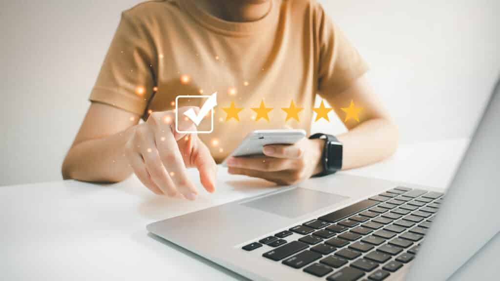 Un utilisateur vérifie les avis en ligne sur son smartphone tout en utilisant un ordinateur portable.