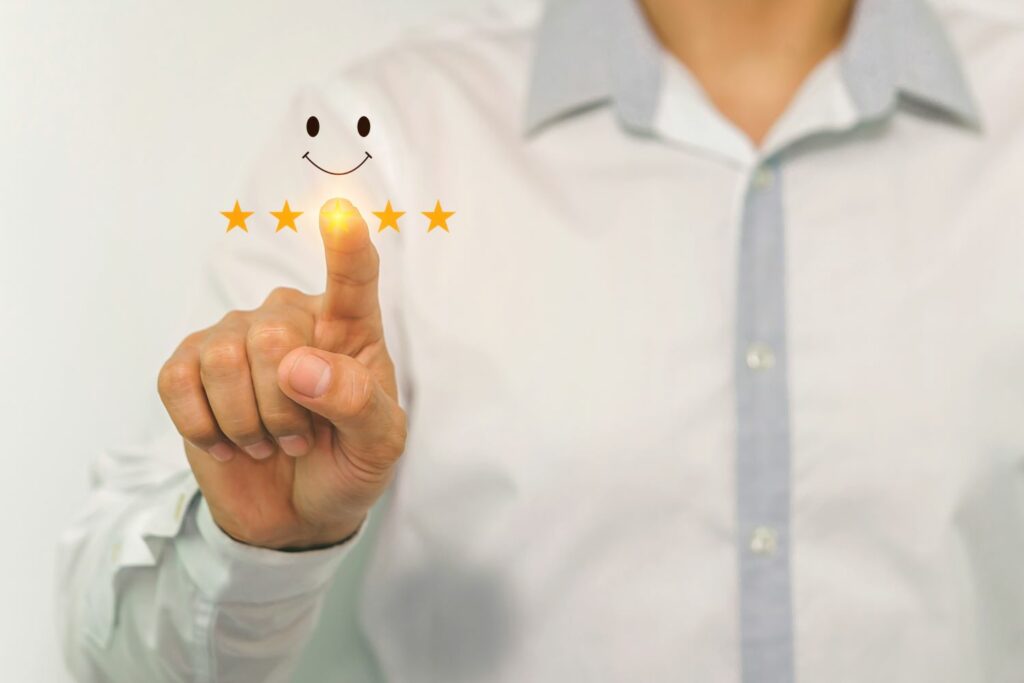 Homme pointant du doigt vers un smiley heureux et une note de cinq étoiles, symbolisant une évaluation parfaite d'un  parcours d'achat. 