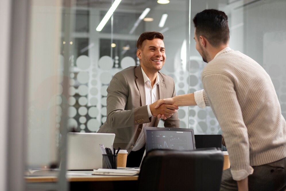 Deux hommes se serrent la main dans un bureau moderne, illustrant une relation client réussie et une collaboration professionnelle