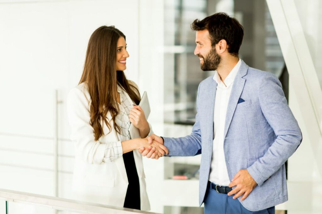 Deux professionnels en tenue de travail se serrent la main dans un bureau, illustrant le marketing relationnel efficace