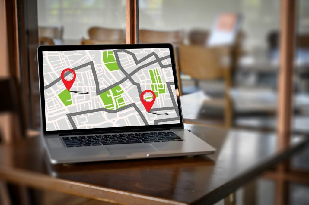 Ordinateur portable affichant une carte numérique avec des repères de localisation rouges, symbolisant la navigation pour le SEO local.