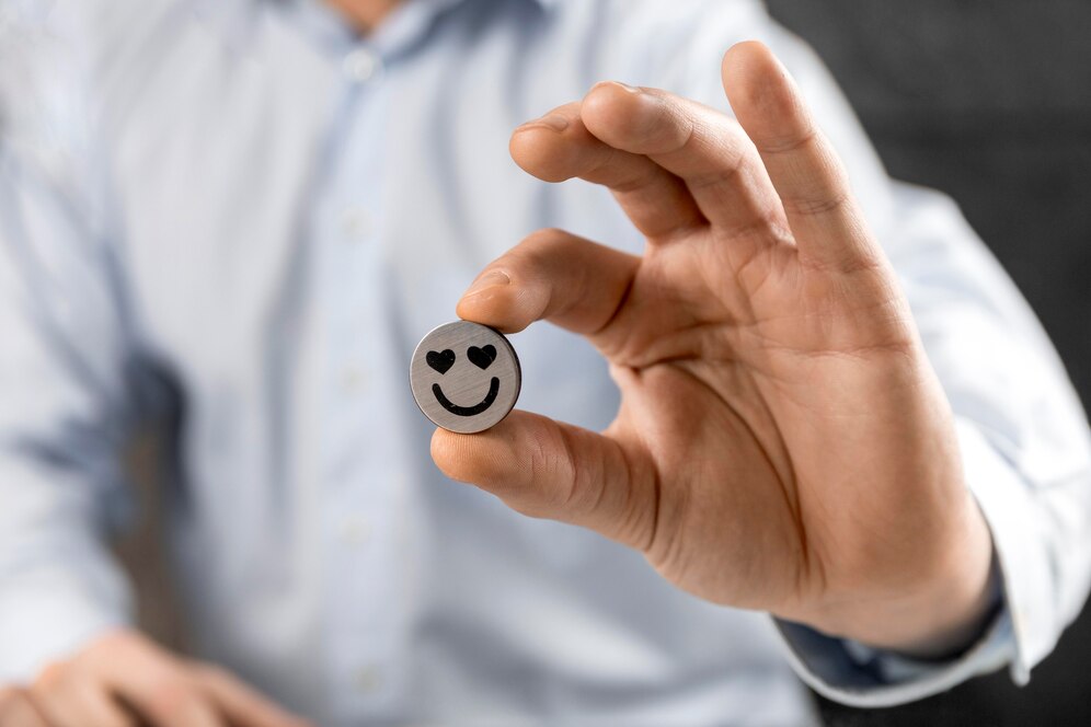 Un homme en chemise tient un émoticône souriant avec des yeux en forme de cœur, symbolisant la satisfaction client et une relation client positive.

